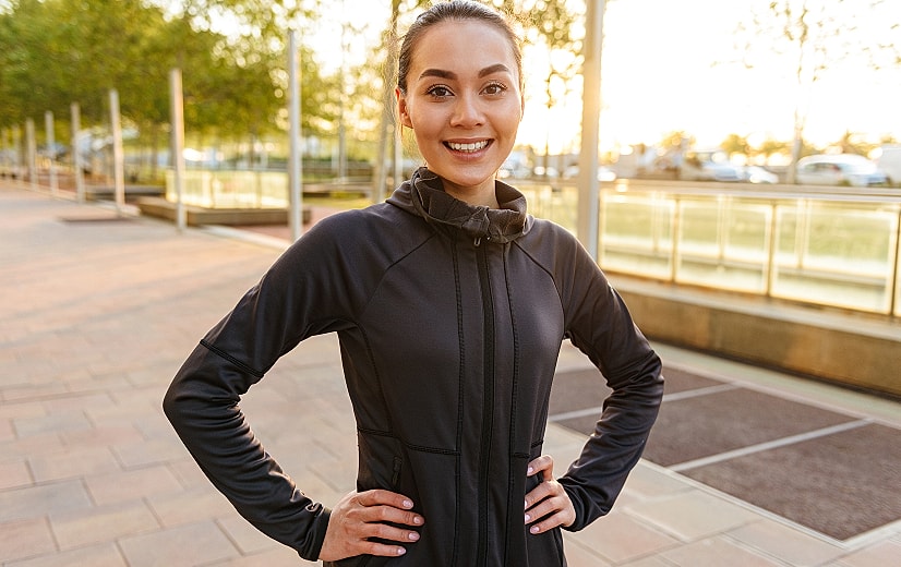 Smiling woman in athletic attire outdoors.