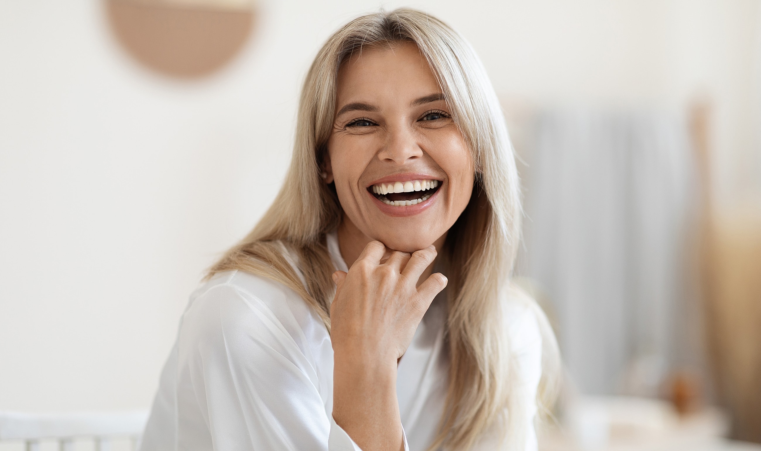 Smiling woman with long blonde hair indoors.